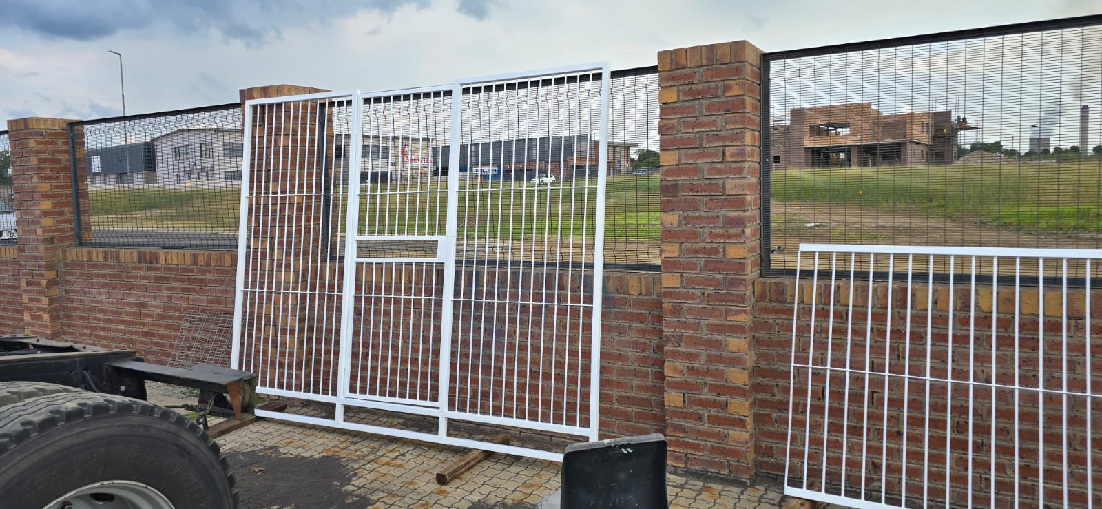 White steel gate installation with brick pillars